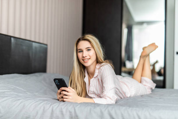 istock Relaxed young woman at home reading a text message in her bright bedroom 1328643167