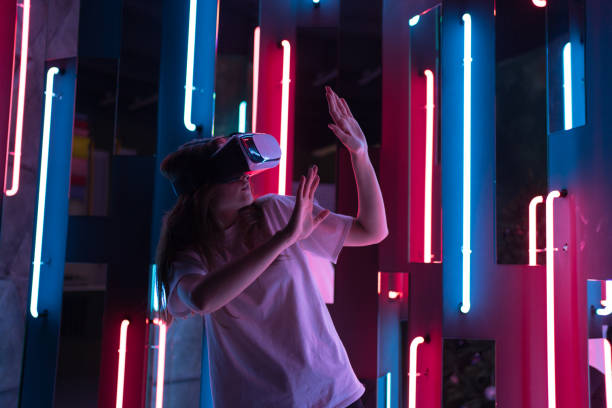 istock A young woman in headset is explore VR. Neon light. A joyful new experience in entertainment 1328645950