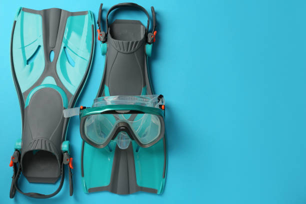 istock Pair of turquoise flippers and mask on light blue background, flat lay. Space for text 1328646788