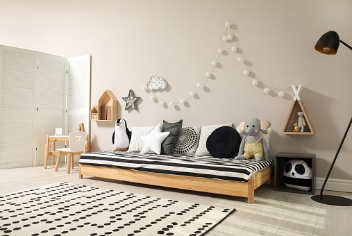 Cute kids room with stylish comfortable floor bed and toys. Montessori interior