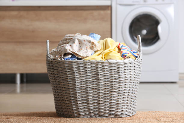 istock Wicker basket with dirty clothes on floor in laundry room 1328647236