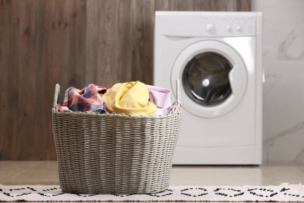 istock Wicker basket with dirty clothes on floor in laundry room 1328648641