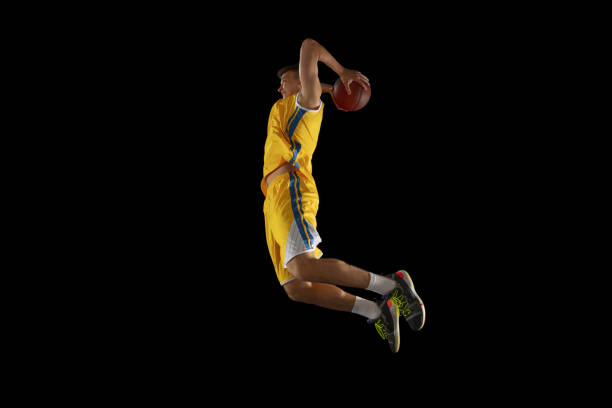 istock Young man, basketball player with a ball training isolated on dark black studio background. Advertising concept. Fit Caucasian athlete practicing with ball. 1328648855