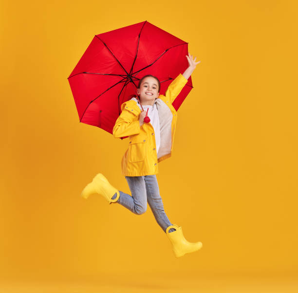 istock Happy kid with umbrella jumping in studio 1328649650