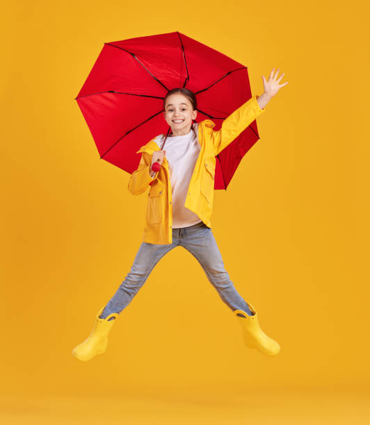 istock Happy kid with umbrella jumping in studio 1328649680