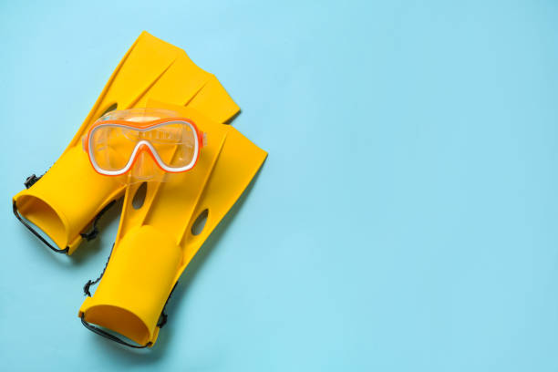 istock Pair of yellow flippers and mask on light blue background, flat lay. Space for text 1328649765