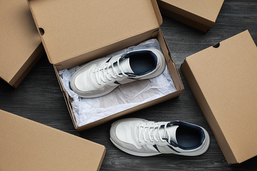 Sneakers and cardboard shoe boxes on wooden floor, flat lay
