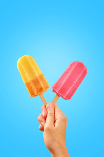 istock Two color popsicles in woman hands on blue background 1328652090