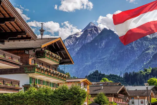 Kaprun village with hotel against Kitzsteinhorn glacier and Austrian flag in Salzburg region, Austrian Alps, Austria