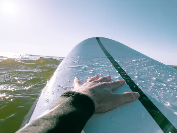 istock Water scene - surfer's hand on a white surfboard. Surfing in sunset. 1328659310