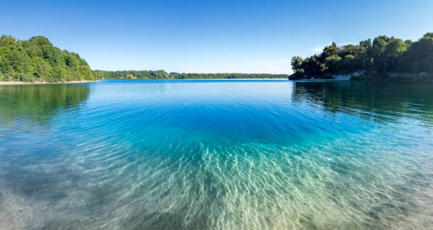 istock Crystal clear lake surrounded by forest. Blue sky on the background. 1328659316