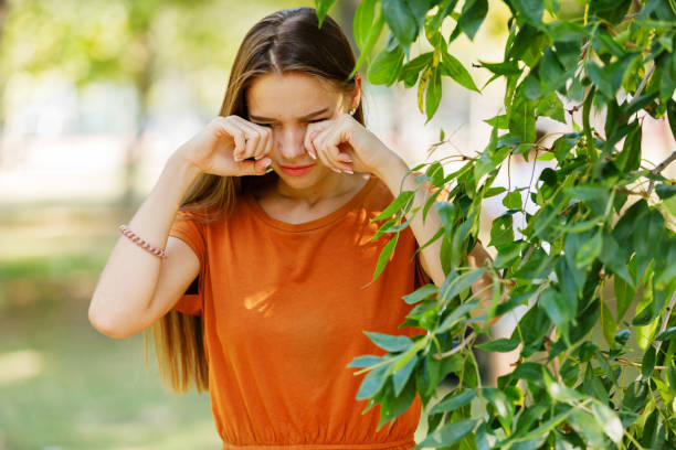 Young Woman is Having Allergy Problems Outside in Nature. A Woman of Caucasian Ethnicity with Long Hairis Rubbing her Eyes Due to Problems with Sight in the Public Park. human eye scratching allergy rubbing stock pictures, royalty-free photos & images