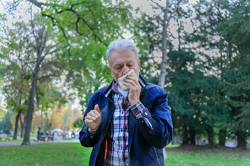 An Older Man is Feeling Sick and Desperate Due to Flu Virus. Senior Man is Using Paper Tissues While Sneezing and Feeling Illness.