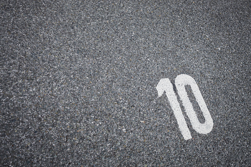 sign on the asphalt, white painted number ten on grey street, space for text