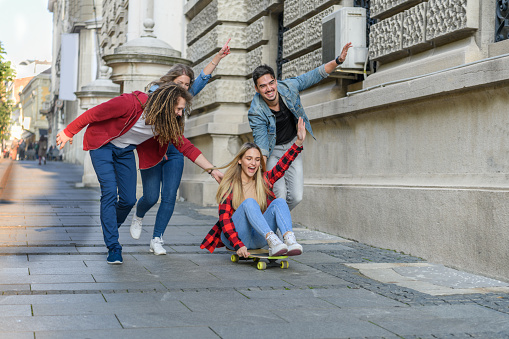 A Happy Men With Girlfriends are Walking in the Streets and Using a Skateboard to Have a Lot of Fun.