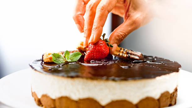 istock Woman placing strawberry on mousse cake 1328664754