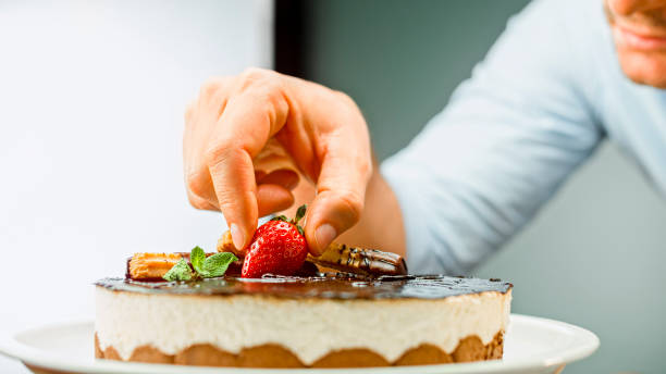 istock Man placing strawberry on mousse cake 1328664765
