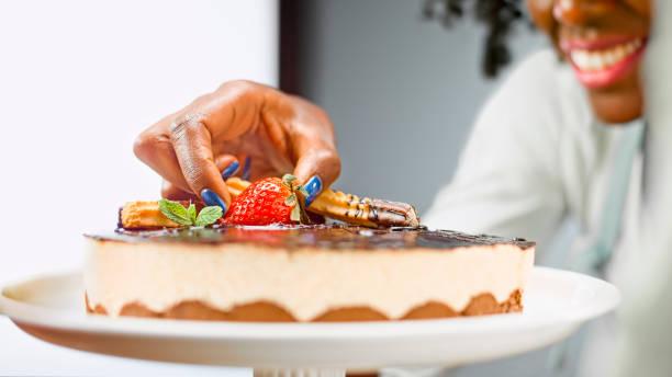 istock Woman placing strawberry on mousse cake 1328664781