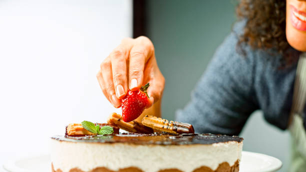 istock Woman placing strawberry on mousse cake 1328664788