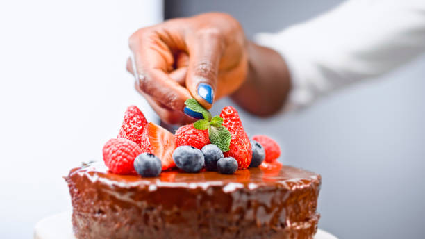 istock Woman placing mint leaf on chocolate cake 1328664810