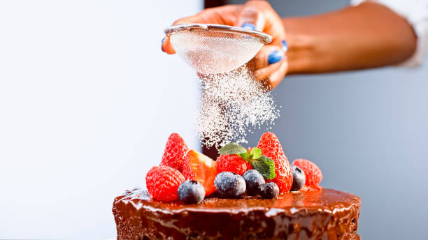 istock Woman dusting caster sugar on chocolate cake 1328664814