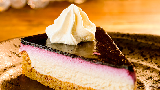 Close-up of slice of cake topped with cream served on plate.