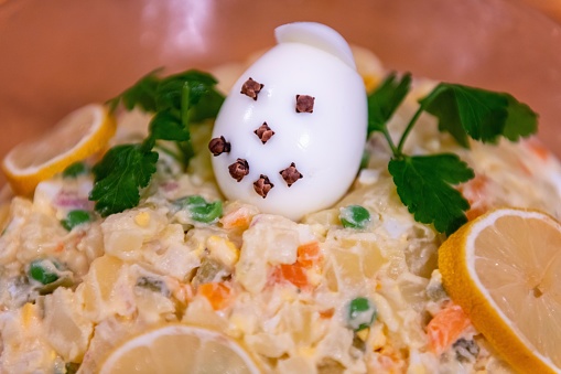 Traditional Czech Christmas potato salad with funny and smiley decorated egg, parsley and citrone as decoration.
