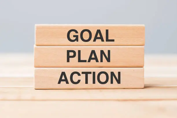 Photo of wooden block with GOAL, PLAN and ACTION on table background