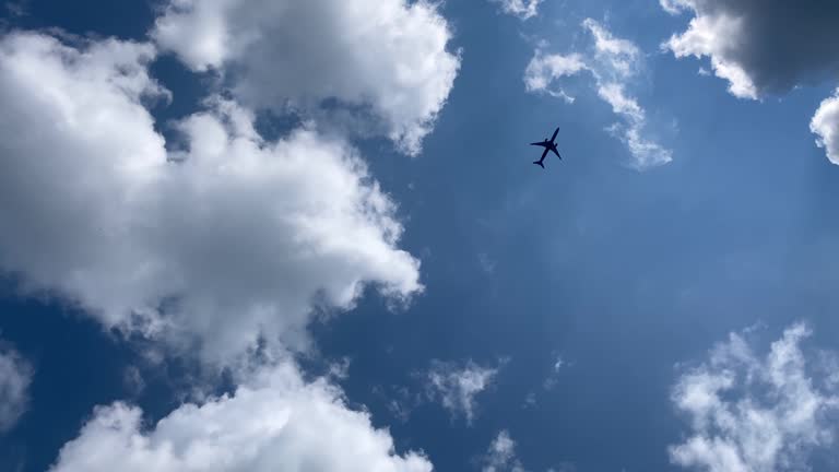 plane is flying in beautiful blue sky with white fluffy clouds. Cumulus clouds