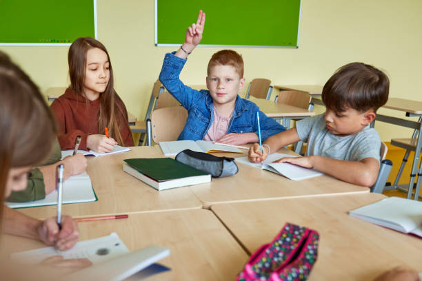 istock Boy with his hand raised in the classroom 1328669132