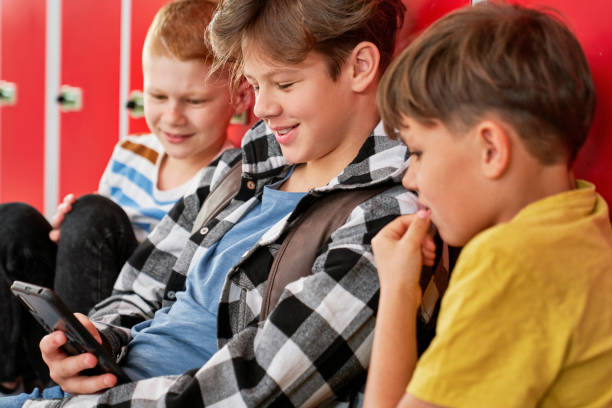 istock Three schoolboys sitting and looking the phone 1328670738