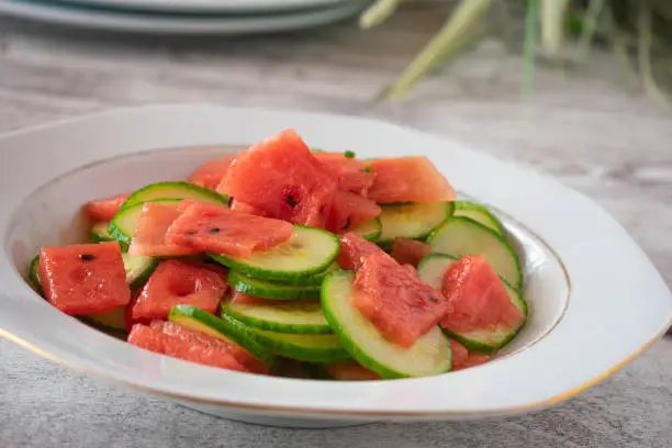 fresh and healthy summer salad with sliced cucumber and melon cubes marinated with lemon juice and served on a plate. Closeup and front view