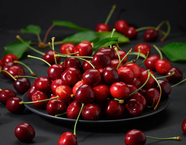 istock ripe red cherries in a ceramic plate on a black wooden table 1328672301