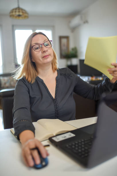 istock Heavy working from home. Woman using papers to cool herself 1328672454