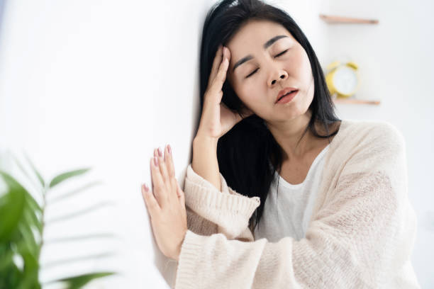 Asian woman having problem with Meniere's disease, fainting or dizziness hand holding her head Asian woman having problem with Meniere's disease, fainting or dizziness hand holding her head leaning against the wall fainted stock pictures, royalty-free photos & images