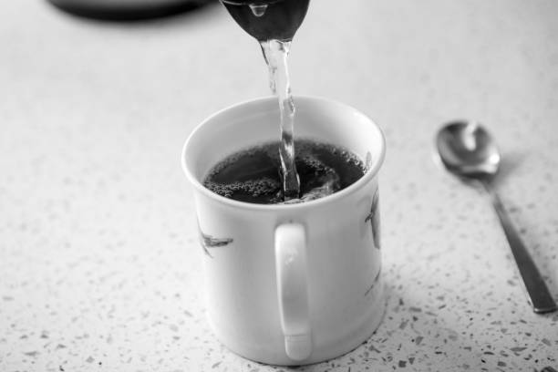 istock Pouring boiling water from a kettle into a mug 1328679773