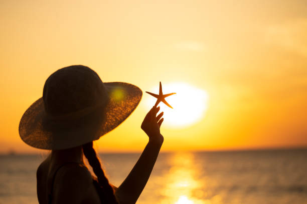 young woman in a hat on the beach young woman in hat with starfish on the beach starfish sunglasses stock pictures, royalty-free photos & images