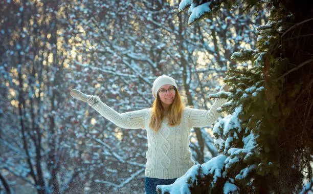 Happy woman plays with a snow in sunny winter day. Girl enjoys winter, frosty day. Playing with snow on winter holidays, a woman throws white, loose snow into the air. Walk in winter forest.