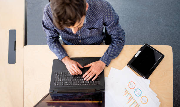 istock Young businessman sitting at his office desk working on a laptop 1328689583