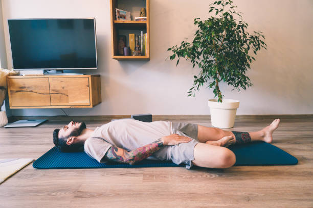 istock Bearded man meditating in Wind Relieving pose at home 1328690664