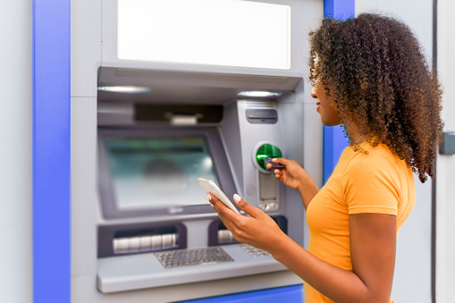 Una mujer negra retirando dinero en un cajero automático photo