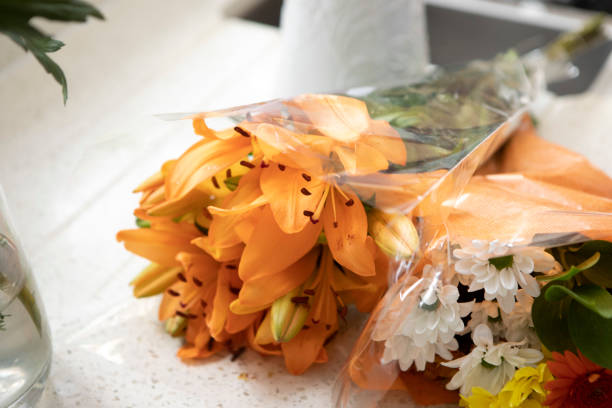 Preparing shop bought flowers at home by the window of a domestic kitchen