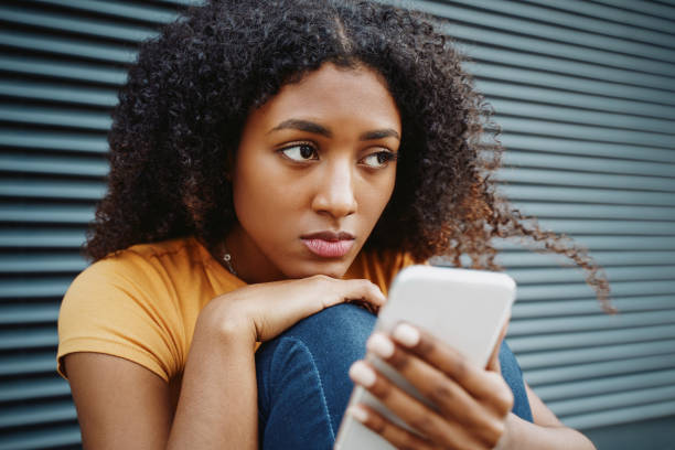 retrato de una chica negra solitaria usando el teléfono celular - mental abuse fotografías e imágenes de stock