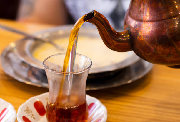 istock Turkish tea is poured from a traditional teapot into a transparent cup. 1328693061