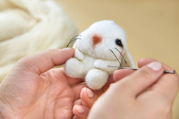 istock Woman's hands hold a toy hare and a needle. 1328693585
