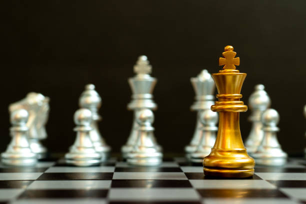 istock Gold king in chess game face with the another silver team on black background (Concept for company strategy, business victory or decision) 1328693650