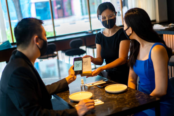 istock Asian waitress with face mask and face shield asking customer to scan QR code for food menu. 1328693719