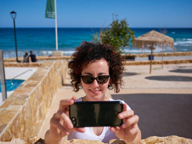 istock Woman taking a selfie next to a beach hut 1328694484