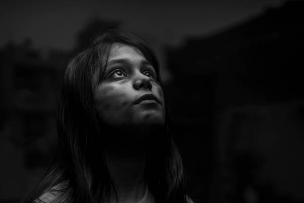 Monochrome portrait of a poor teenager girl looking up. Monochrome  Indian portrait of a poor teenager girl looking up side and praying god. very poor girl. scars on face. torture photos stock pictures, royalty-free photos & images
