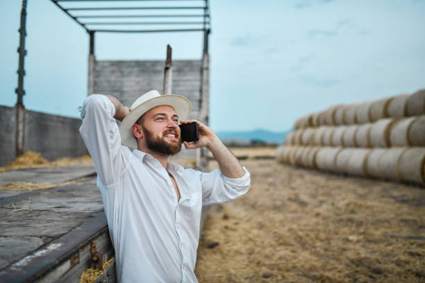 istock Handsome Smiling Farmer Calling Help For Hay Bales Transportation On Field 1328697312
